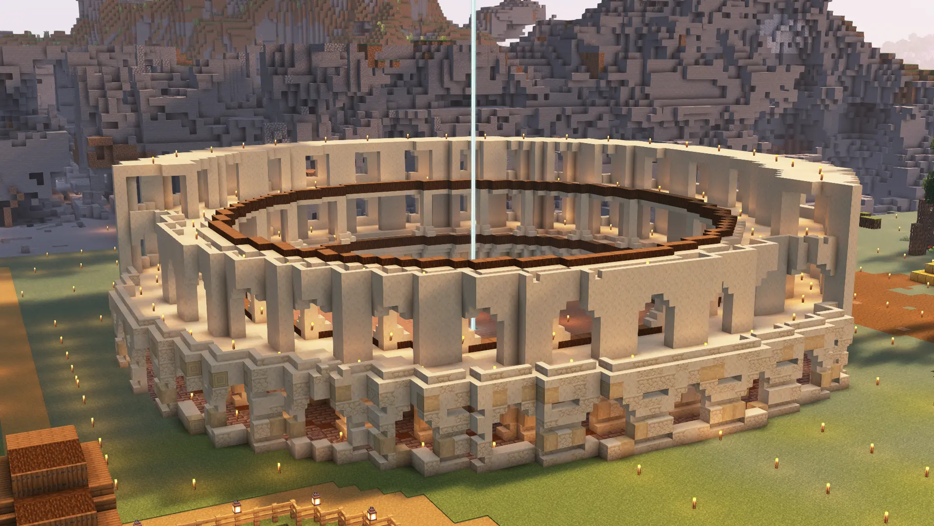 A circular colosseum built out of crumbling sandstone with a white beacon shining out from the center.